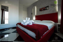 Набор мебели для гостиничного номера: кровать, панель на стену с небольшими прикроватными столиками, письменный стол, шкаф. Мебель изготовлена из ДСП, представлена в отличном цветовом сочетании красного с белым. Идеальный номер для романтического отдыха пары