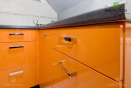 Компактная п-образная кухня оранжевого цвета с навесными шкафчиками белого цвета.