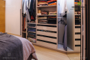 Объемный шкаф с большим количеством полок и зеркалом для хранения одежды, цвет - бежевый. В комнате расположен около кровати