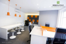 Офисная мебель из ДСП белого и оранжевого цветов. Помимо офисных столов и тумб в набор входит встроенный шкаф и полки для хранения 