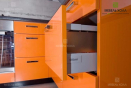 Компактная п-образная кухня оранжевого цвета с навесными шкафчиками белого цвета.
